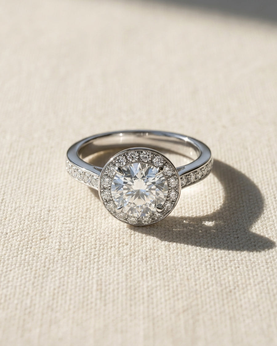 Platinum engagement ring with a round diamond halo and pavé band.