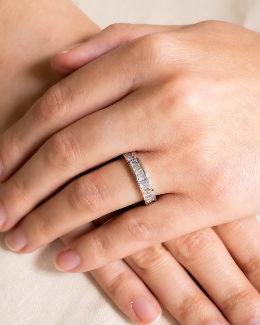 Platinum eternity ring with hinged baguette diamonds on a hand.