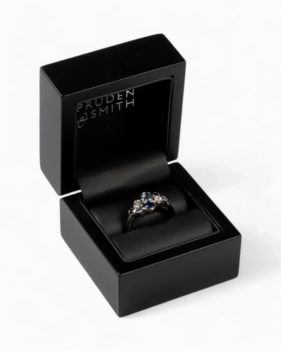 Platinum cluster ring with sapphires and diamonds in a black jewelry box