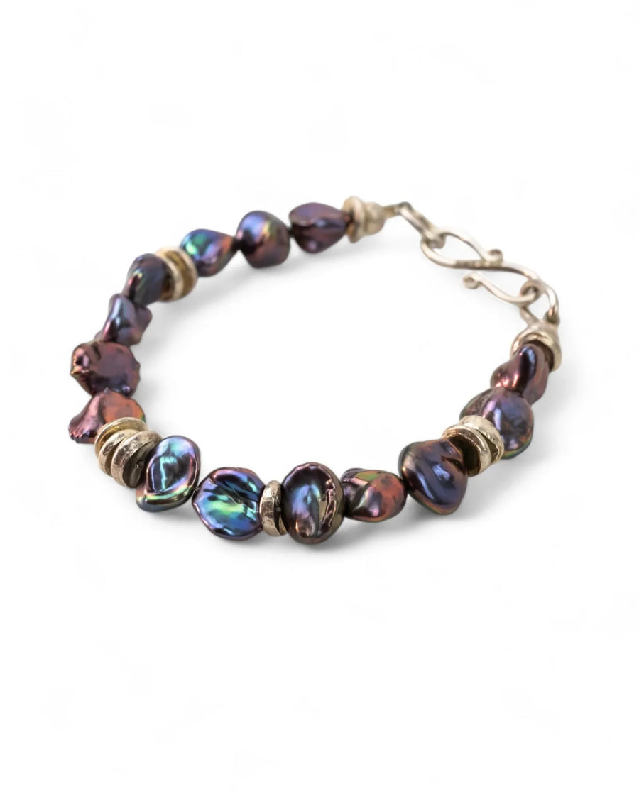 Handmade bracelet with black keshi pearls and silver discs on a white background