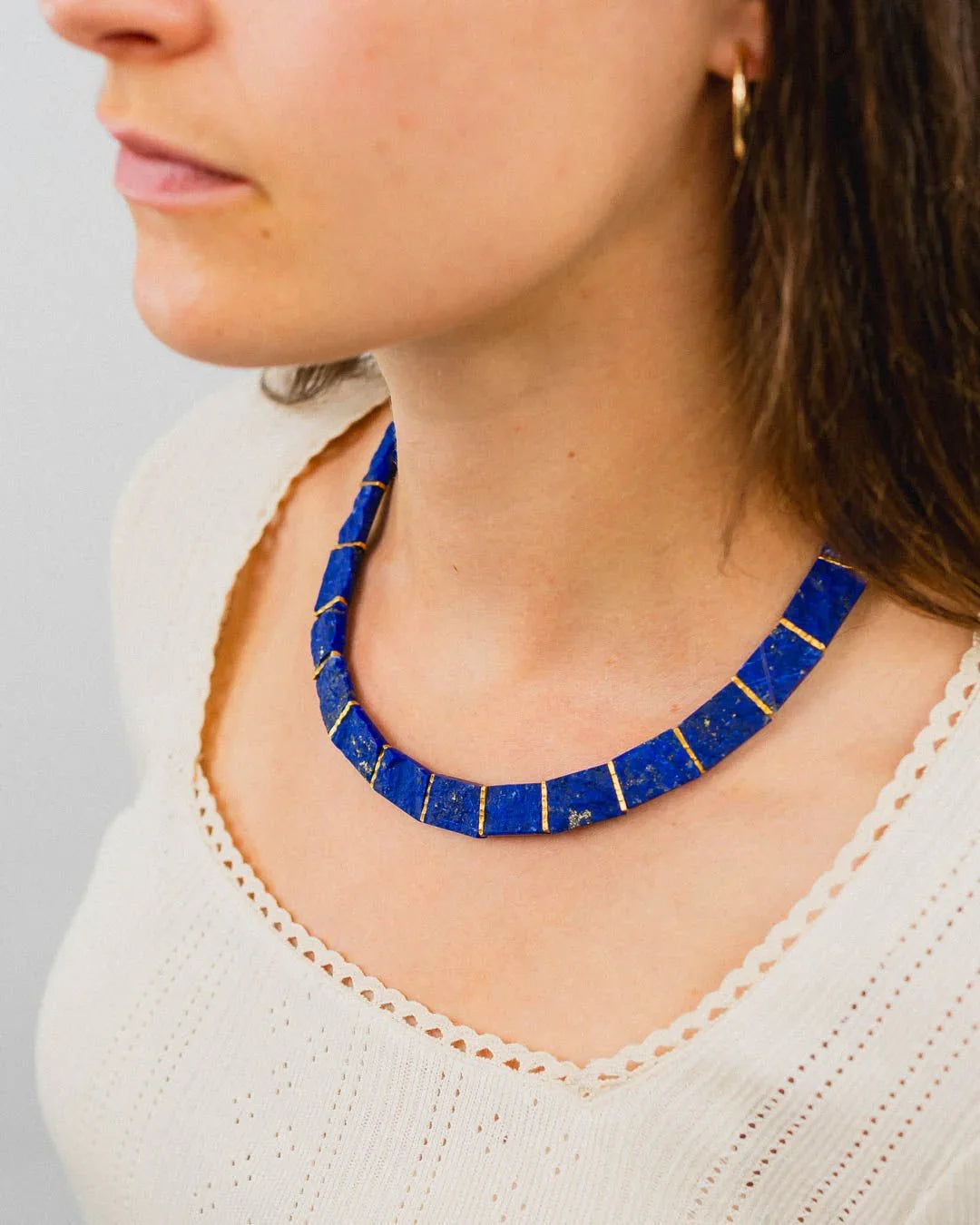 woman wearing a bold lapis lazuli collar necklace with gold lines, elegant handmade jewelry