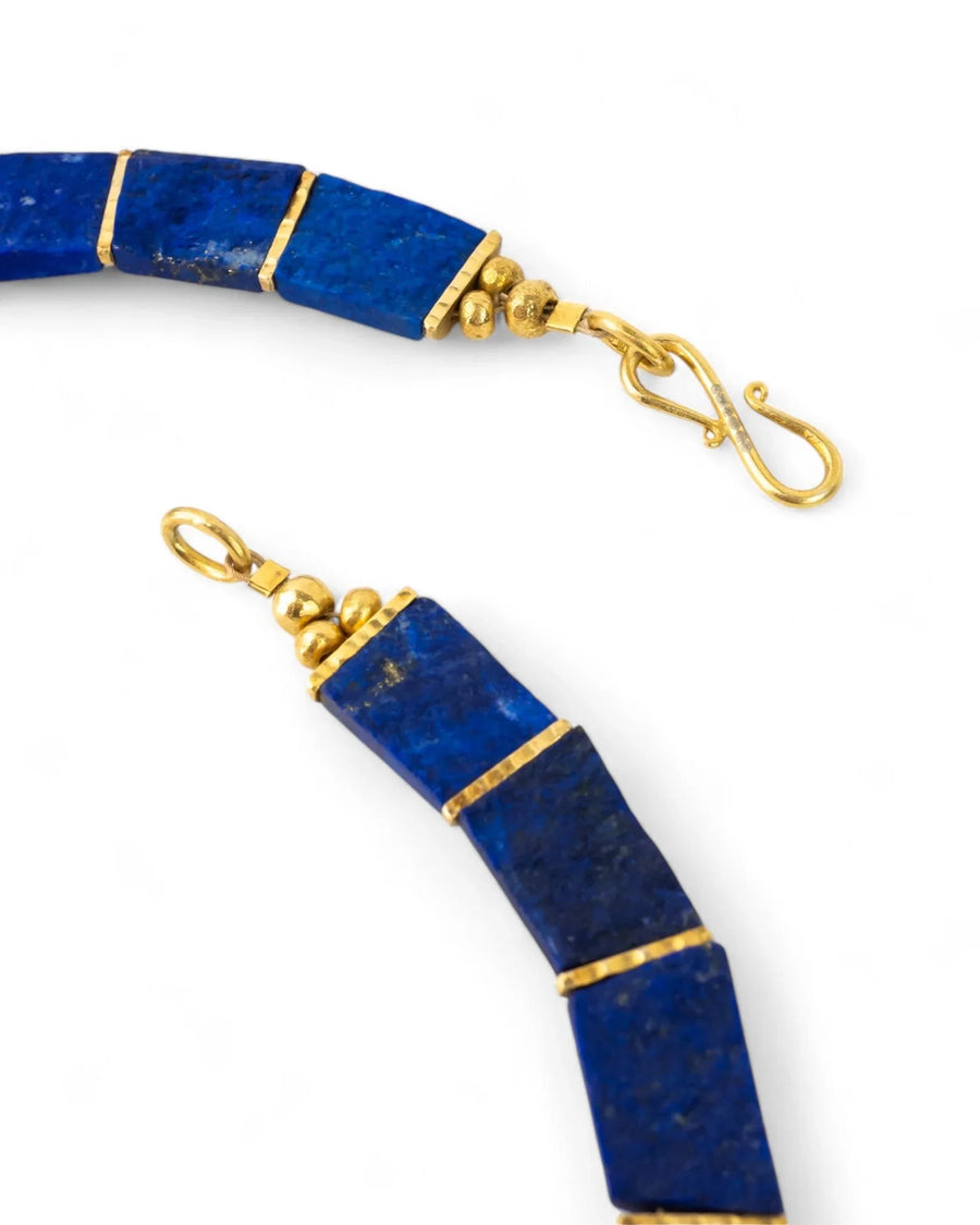 Lapis lazuli collar necklace with gold detailing and clasp, close-up on white background
