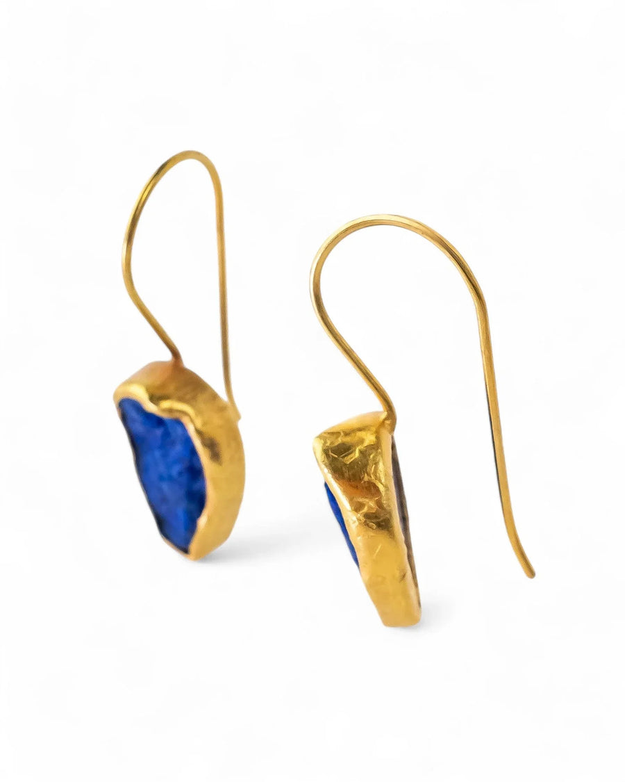 Handmade gold drop earrings with raw blue lapis lazuli stones on white background