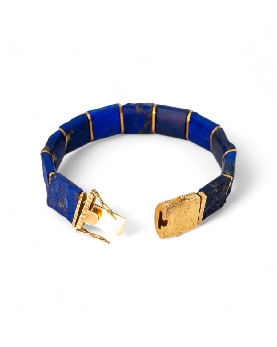Blue lapis lazuli and gold bracelet with rectangular segments and a gold clasp on white background