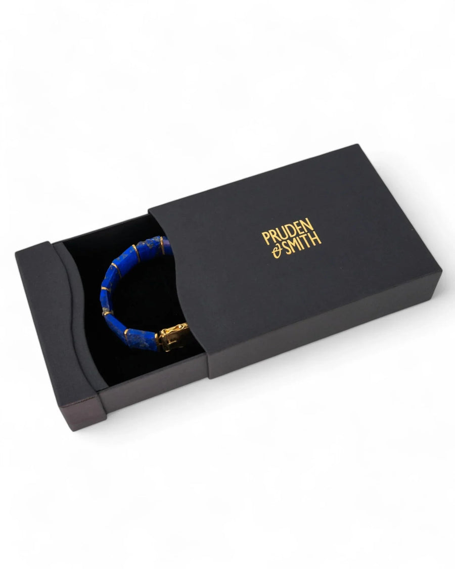 Lapis lazuli and gold bracelet in a black gift box on a white background