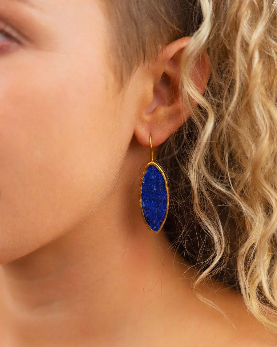 Gold drop earring with marquise-shaped blue lapis lazuli stone worn on ear