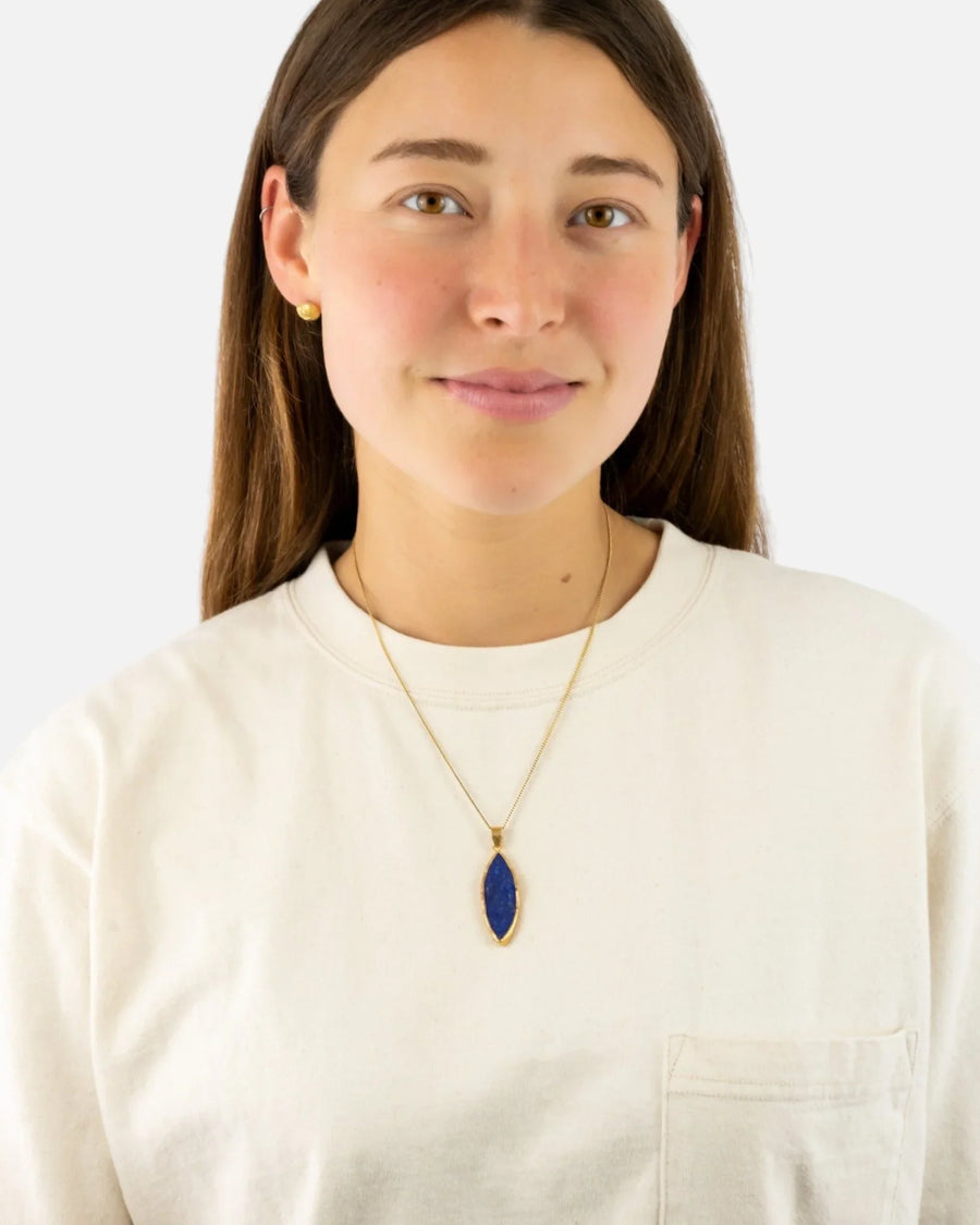 Woman wearing marquise-shaped lapis lazuli pendant on a gold chain necklace
