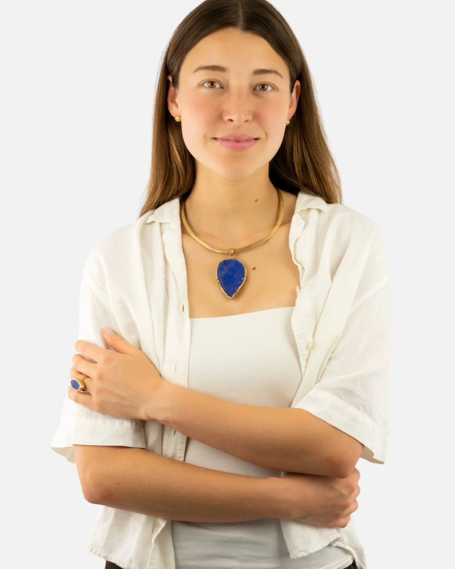 Woman wearing a gold and lapis lazuli necklace with a matching marquise lapis ring.