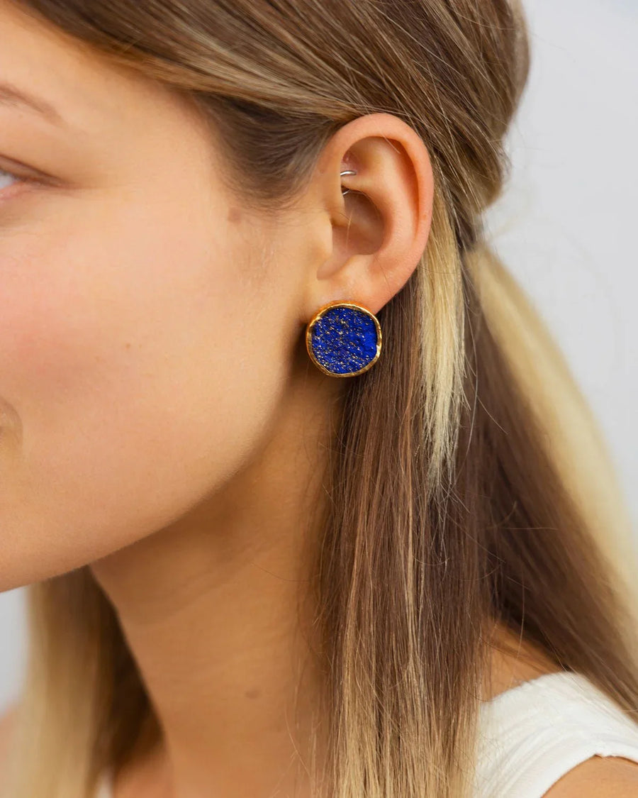 Woman wearing large round lapis lazuli silver stud earring with gold rim