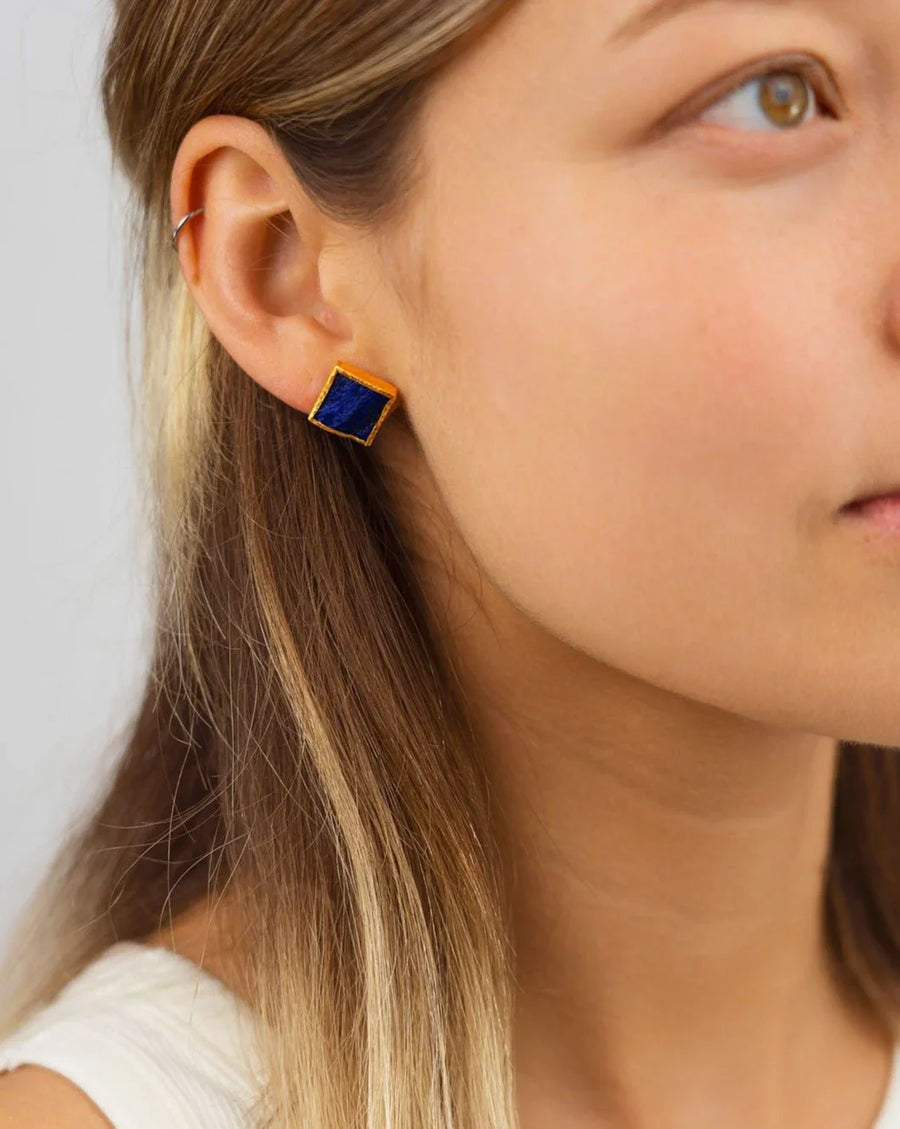Woman wearing square lapis lazuli stud earring with gold setting