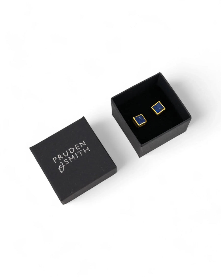 Gold square stud earrings with blue lapis lazuli stones in a black gift box