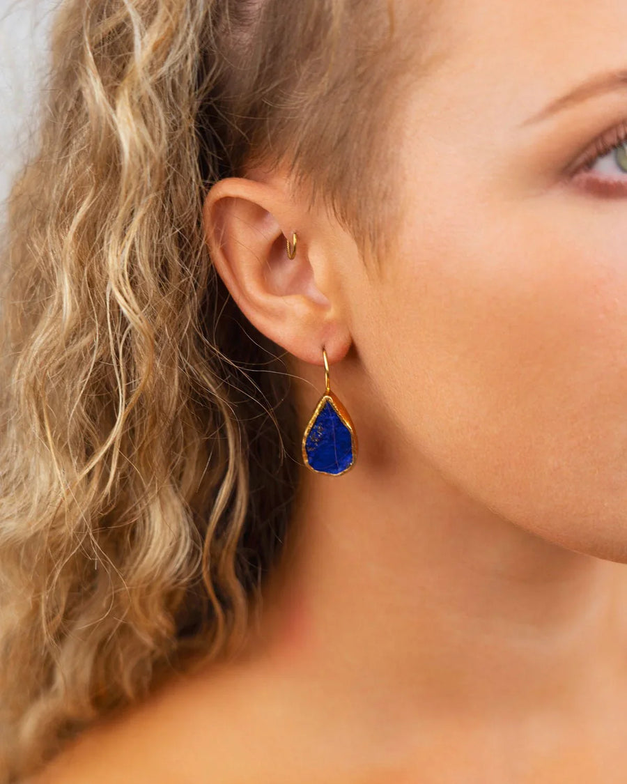 Teardrop lapis lazuli gold drop earring worn on ear, artisan gemstone jewellery