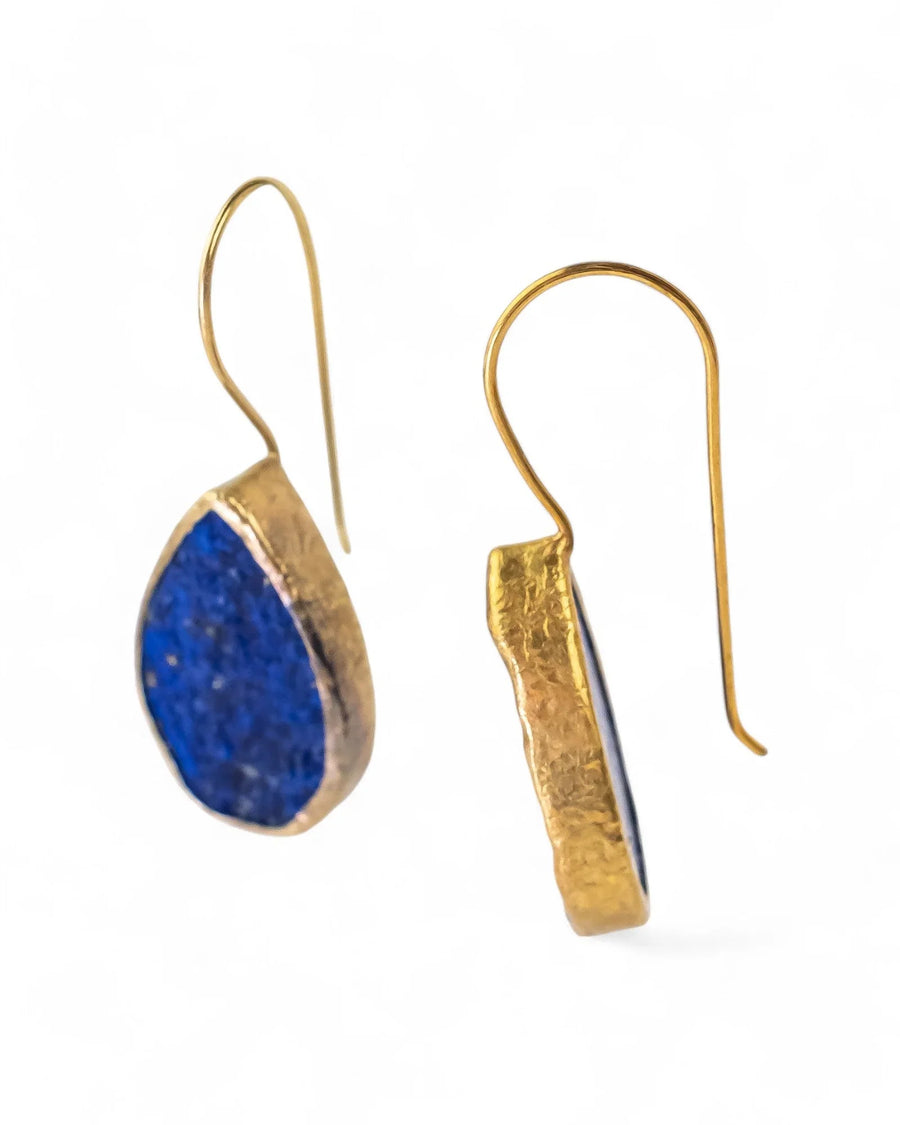 Handcrafted teardrop lapis lazuli earrings with textured gold setting on white background