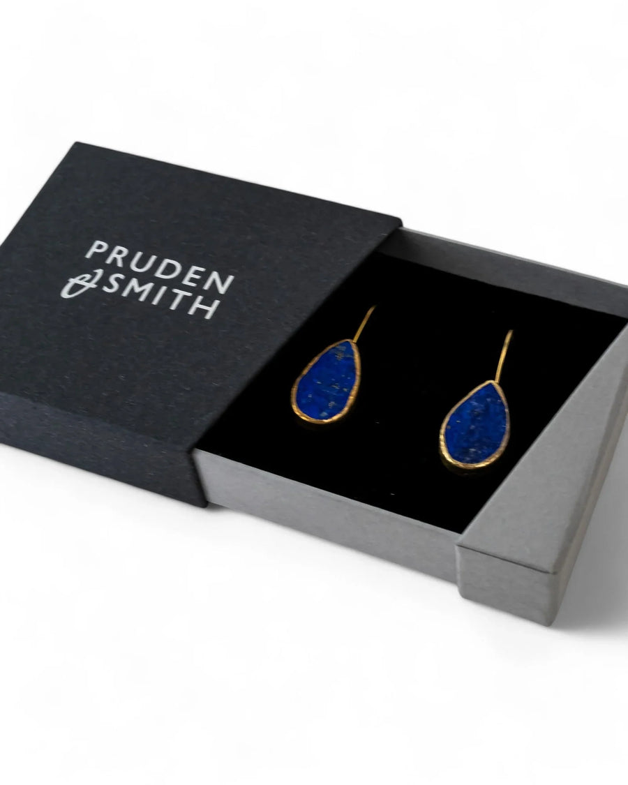 Lapis lazuli teardrop earrings with gold edging in a gray jewelry box