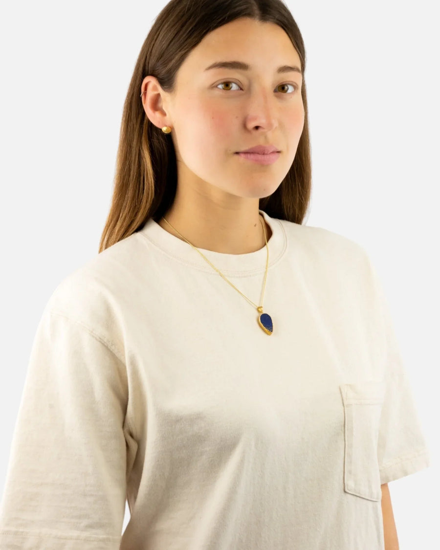 Woman wearing a lapis lazuli pendant in yellow gold on a simple chain necklace