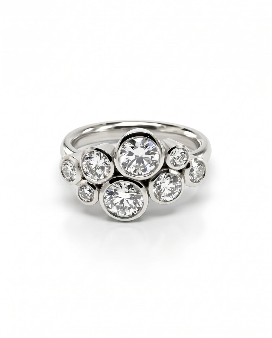 Silver engagement ring featuring a cluster of round diamonds in bezel settings on a polished band.