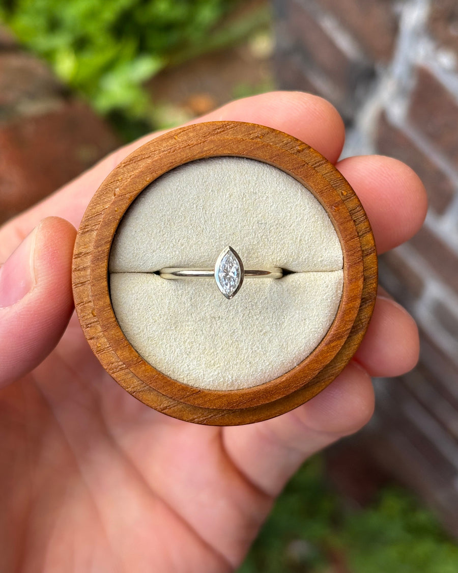 Marquise cut diamond engagement ring in 9ct white gold with a bezel setting inside a wooden ring box.