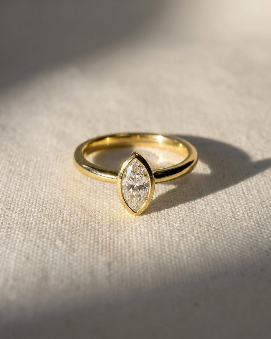 18ct yellow gold engagement ring with a 1ct marquise cut lab-grown diamond in a bezel setting.