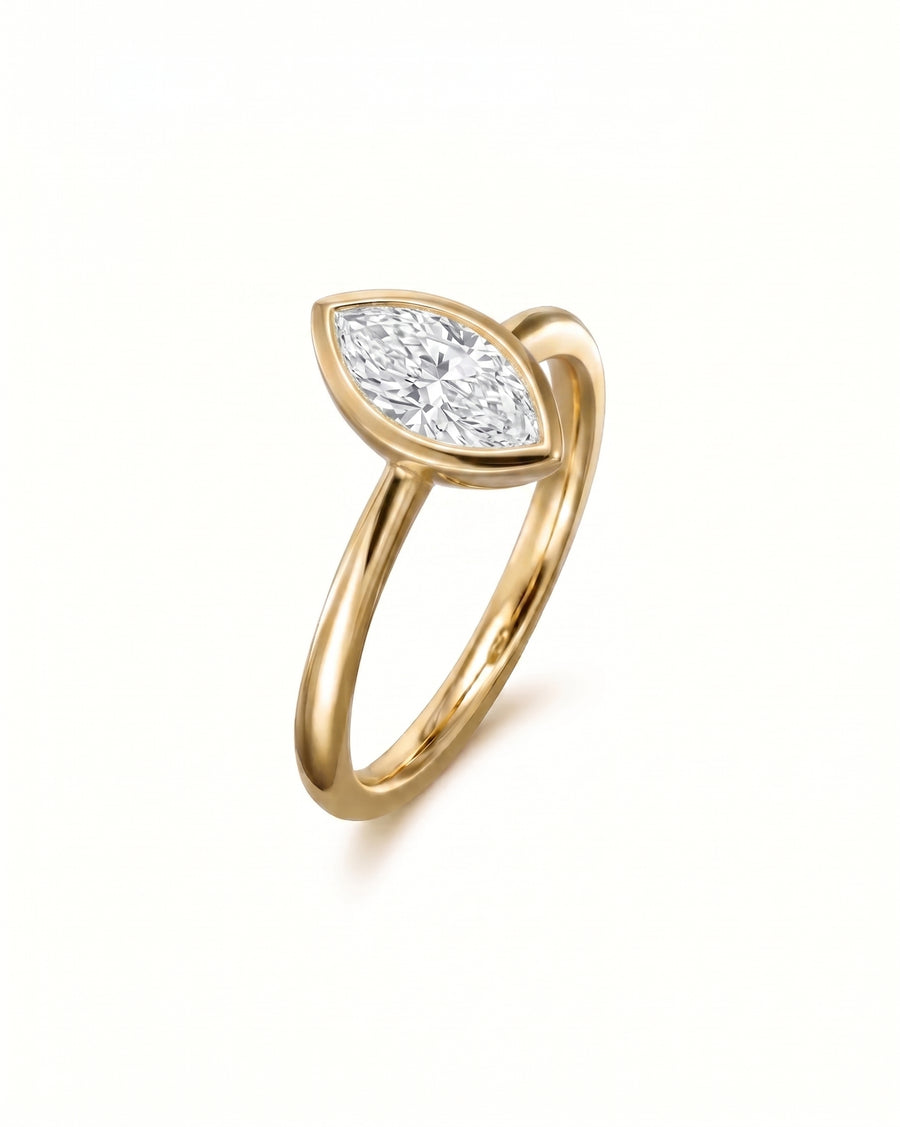Gold engagement ring with a marquise cut diamond in a bezel setting.