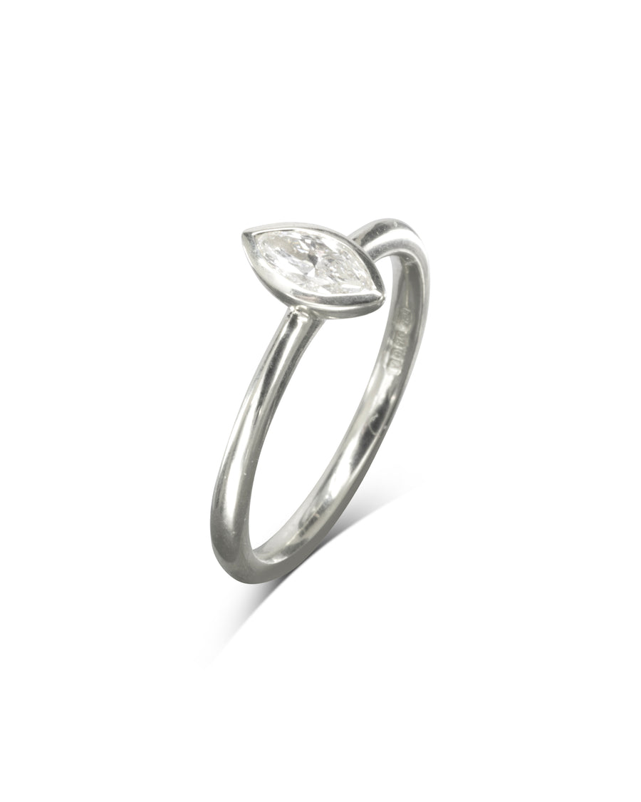 Silver ring with a marquise cut diamond in a bezel setting.
