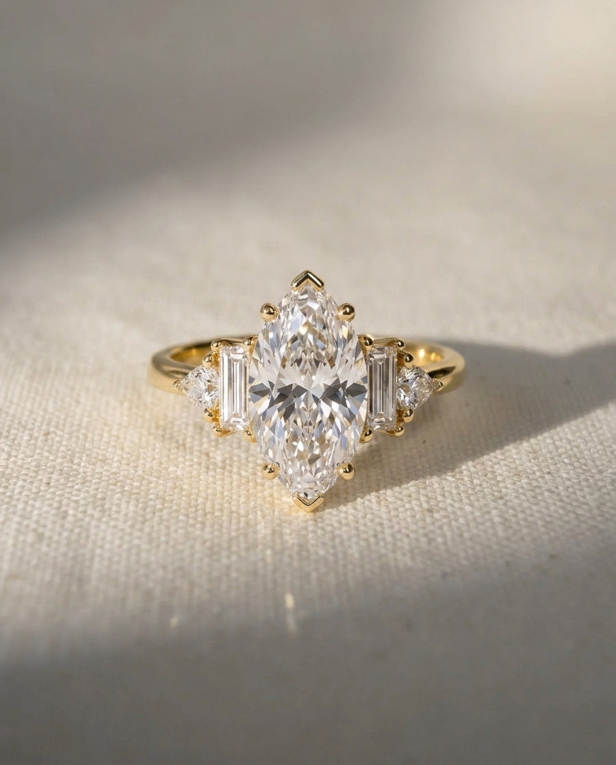 Gold marquise cut diamond engagement ring with claw side stones.
