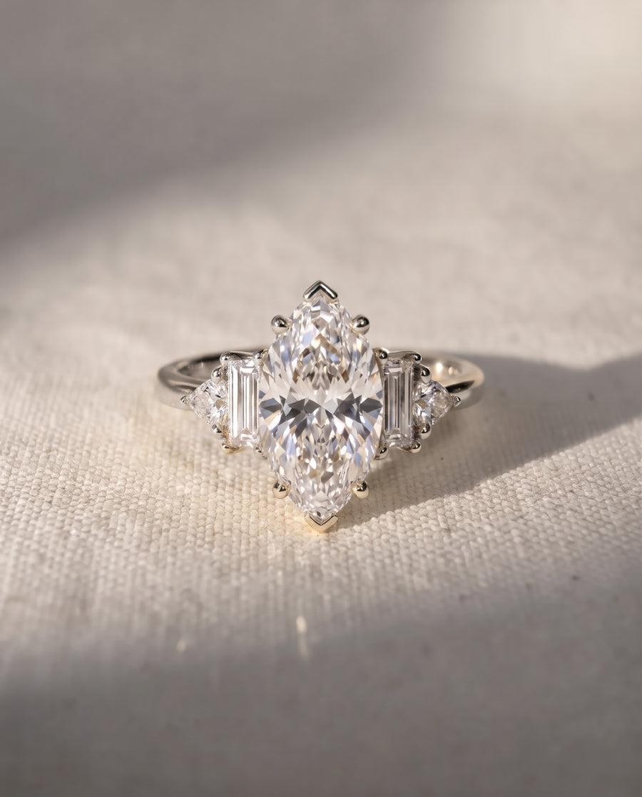 Marquise cut diamond engagement ring with baguette and trillion side stones set in a silver-toned metal band.
