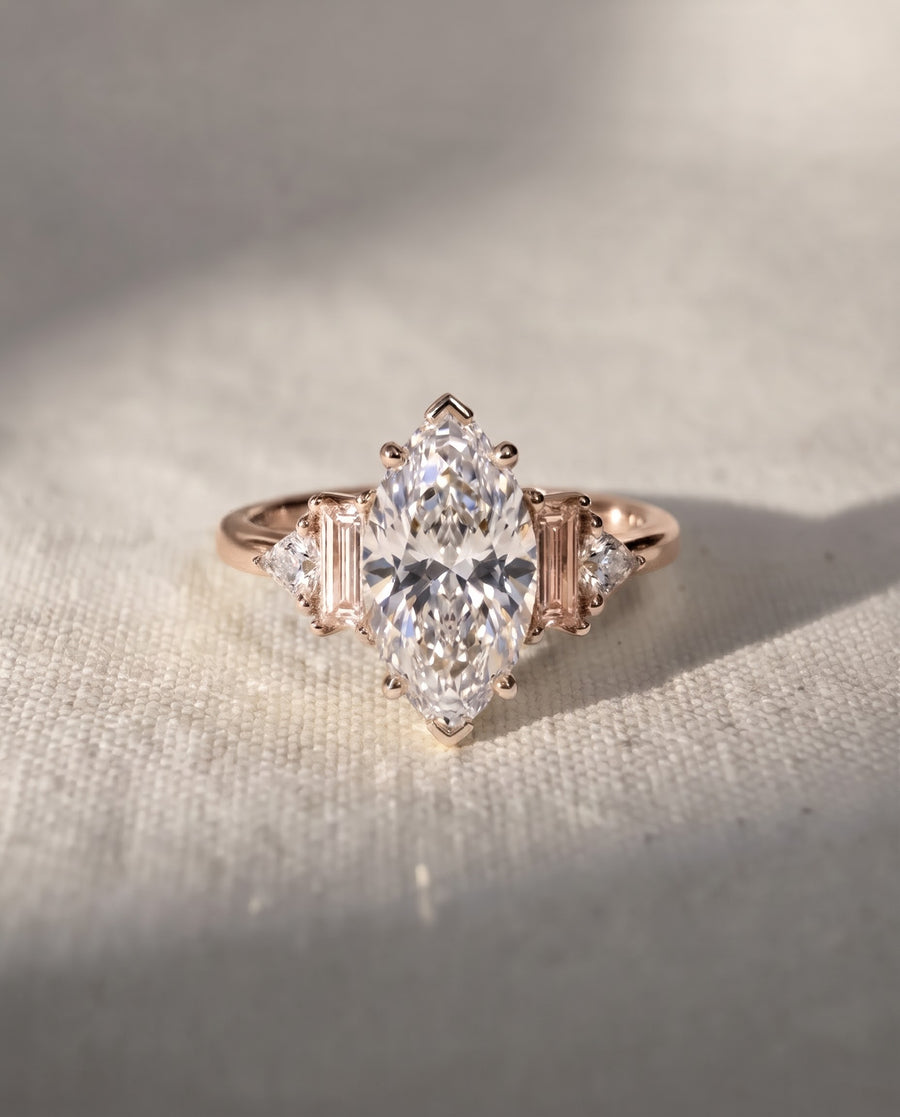 Rose gold engagement ring featuring a marquise cut center diamond with baguette and trillion side stones.