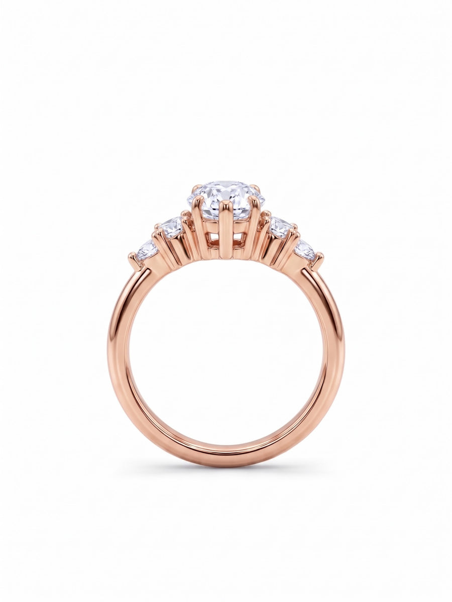 Rose gold engagement ring with a central marquise cut diamond and small side stones in claw settings.