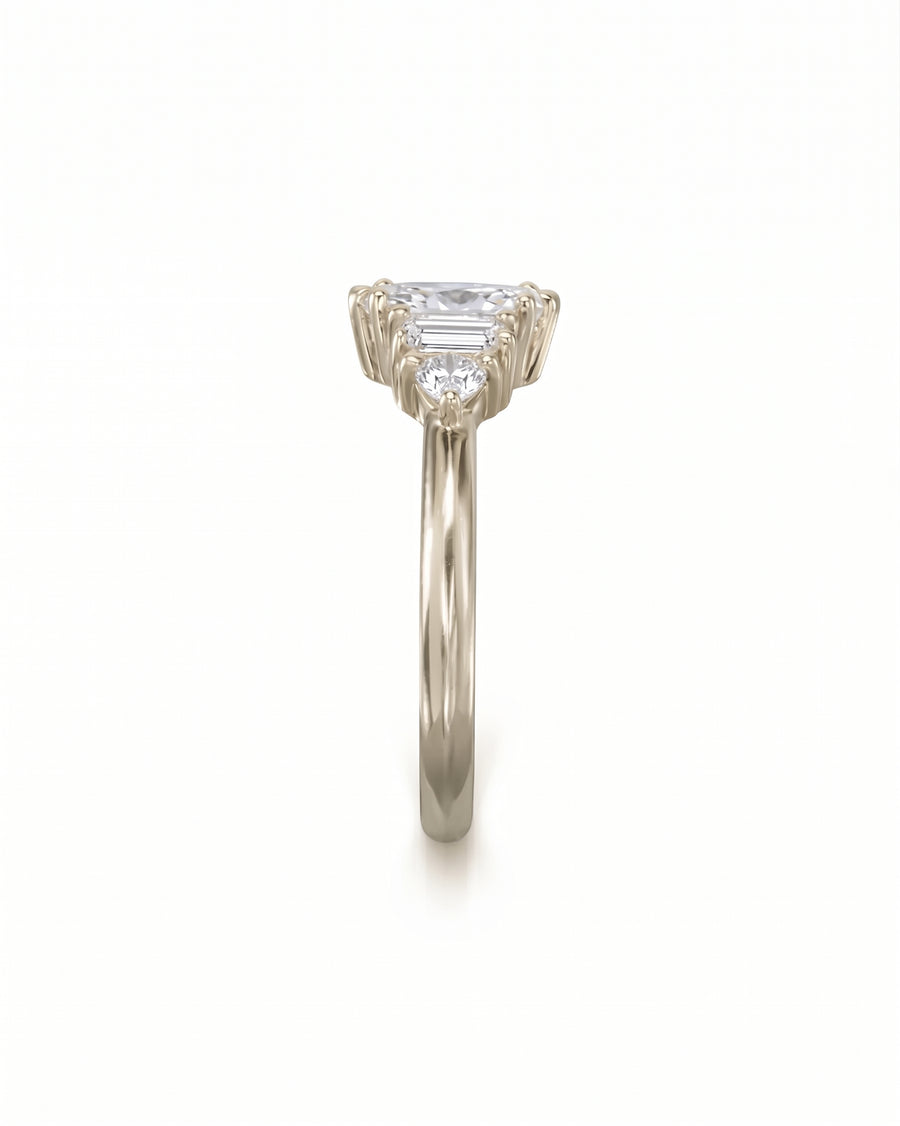 Gold engagement ring with a marquise center stone, baguette side stones, and round accent diamonds.