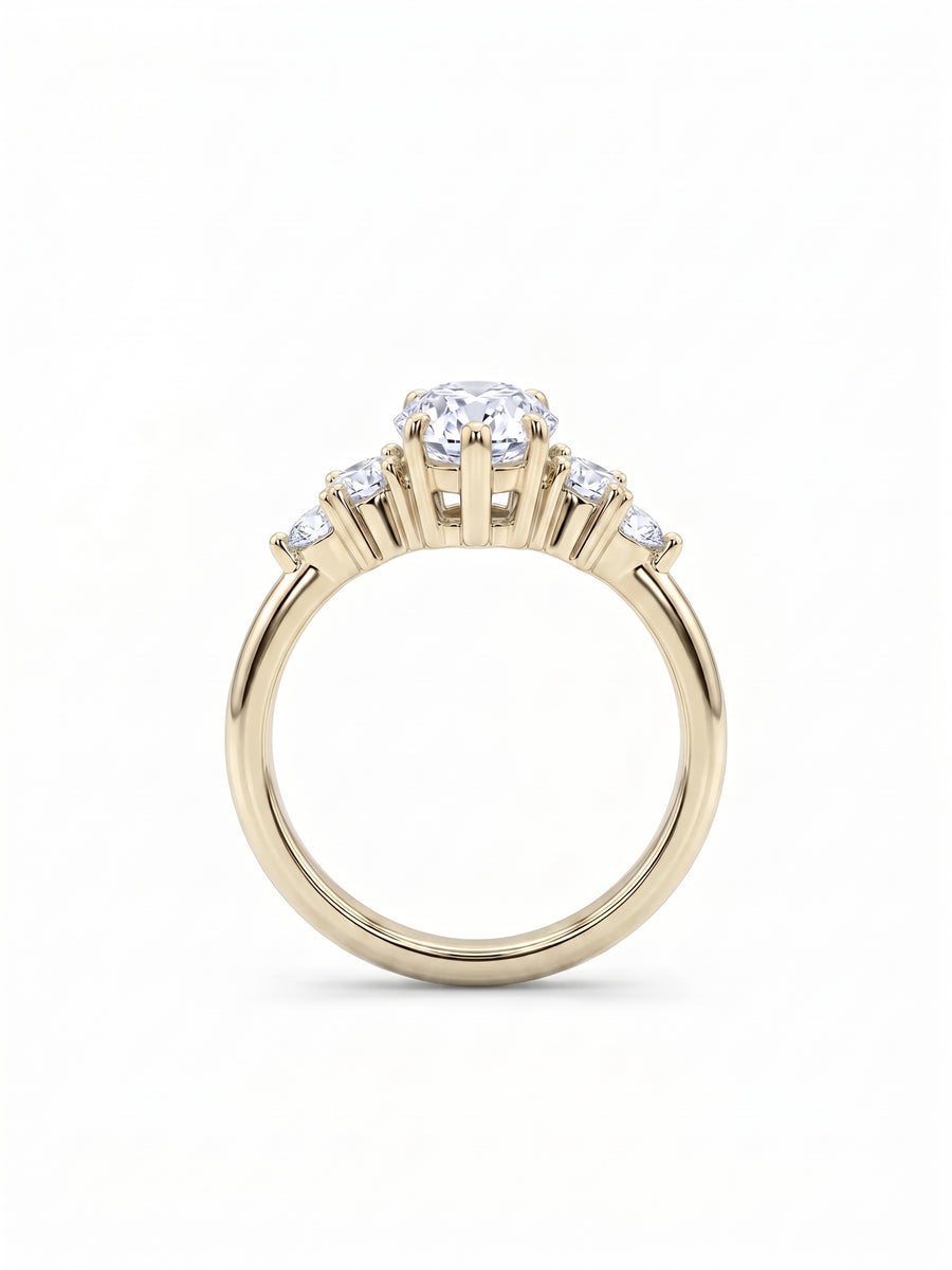 Gold engagement ring with a central marquise cut diamond and smaller side stones in a claw setting.