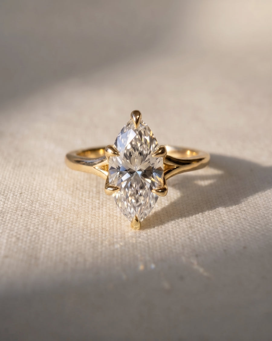 Marquise cut diamond engagement ring set in an 18ct yellow gold tulip claw setting on a textured fabric.