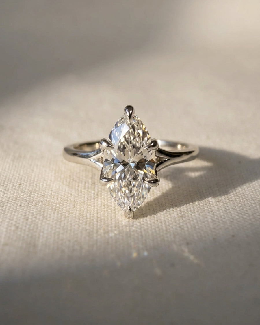 Marquise cut diamond engagement ring set in a platinum tulip claw setting on a textured surface.