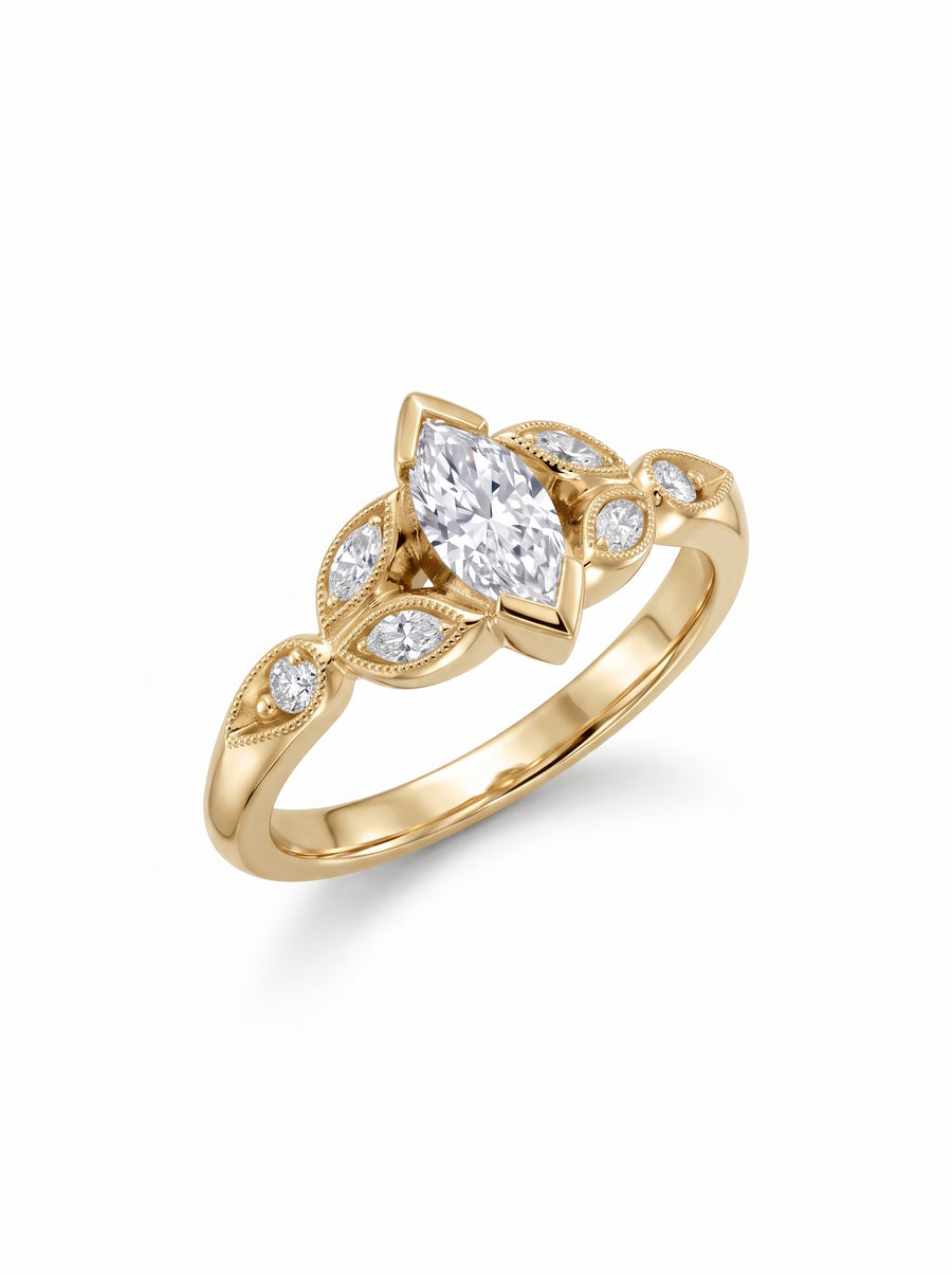 Yellow gold engagement ring featuring a marquise cut center diamond with smaller accent stones and milgrain detailing.