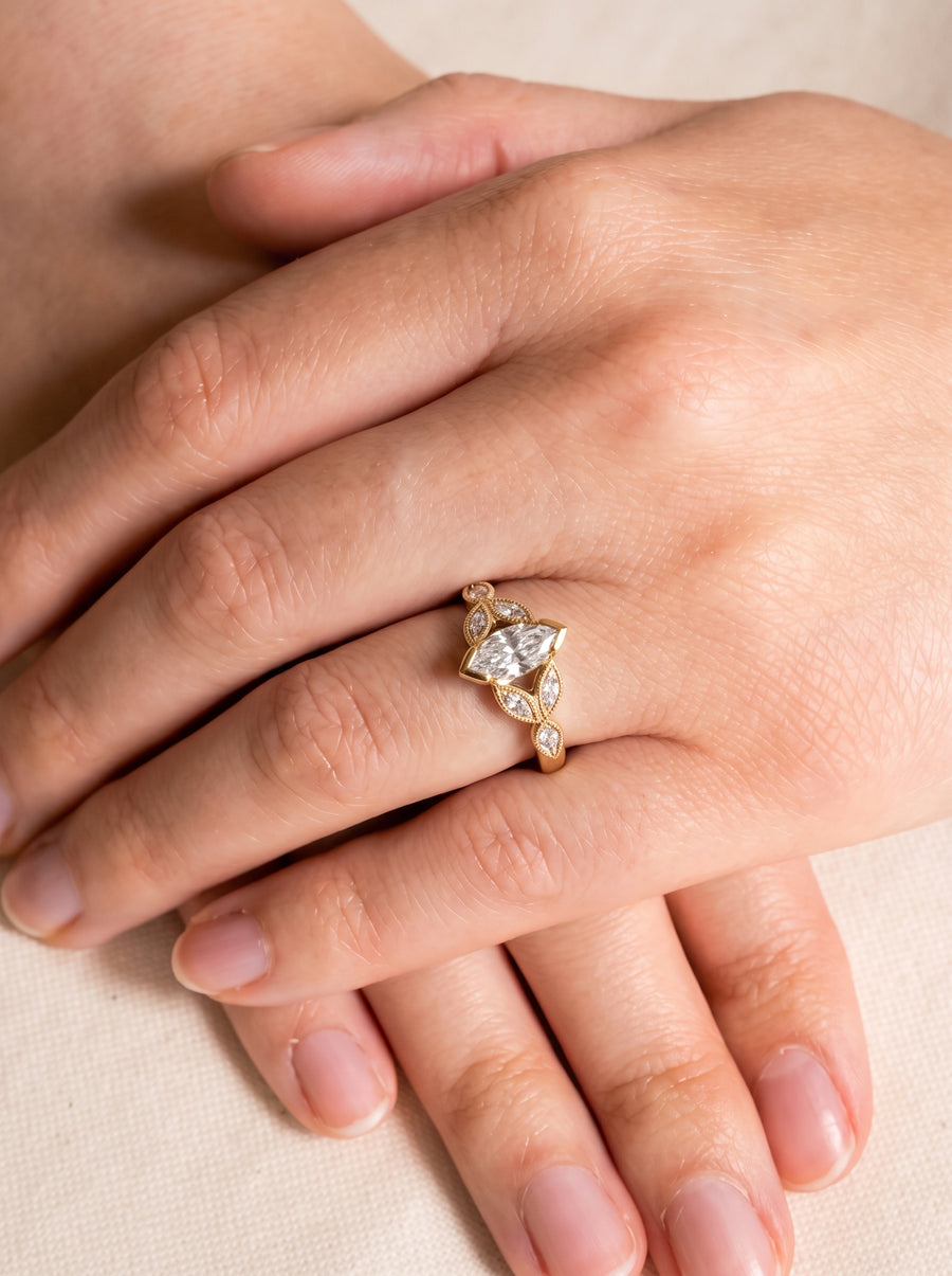 Gold engagement ring with a marquise cut center diamond and smaller accent stones on a vintage band.