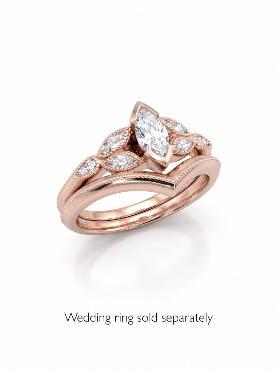 Rose gold vintage engagement ring featuring a marquise cut diamond and smaller accent stones on a chevron band.