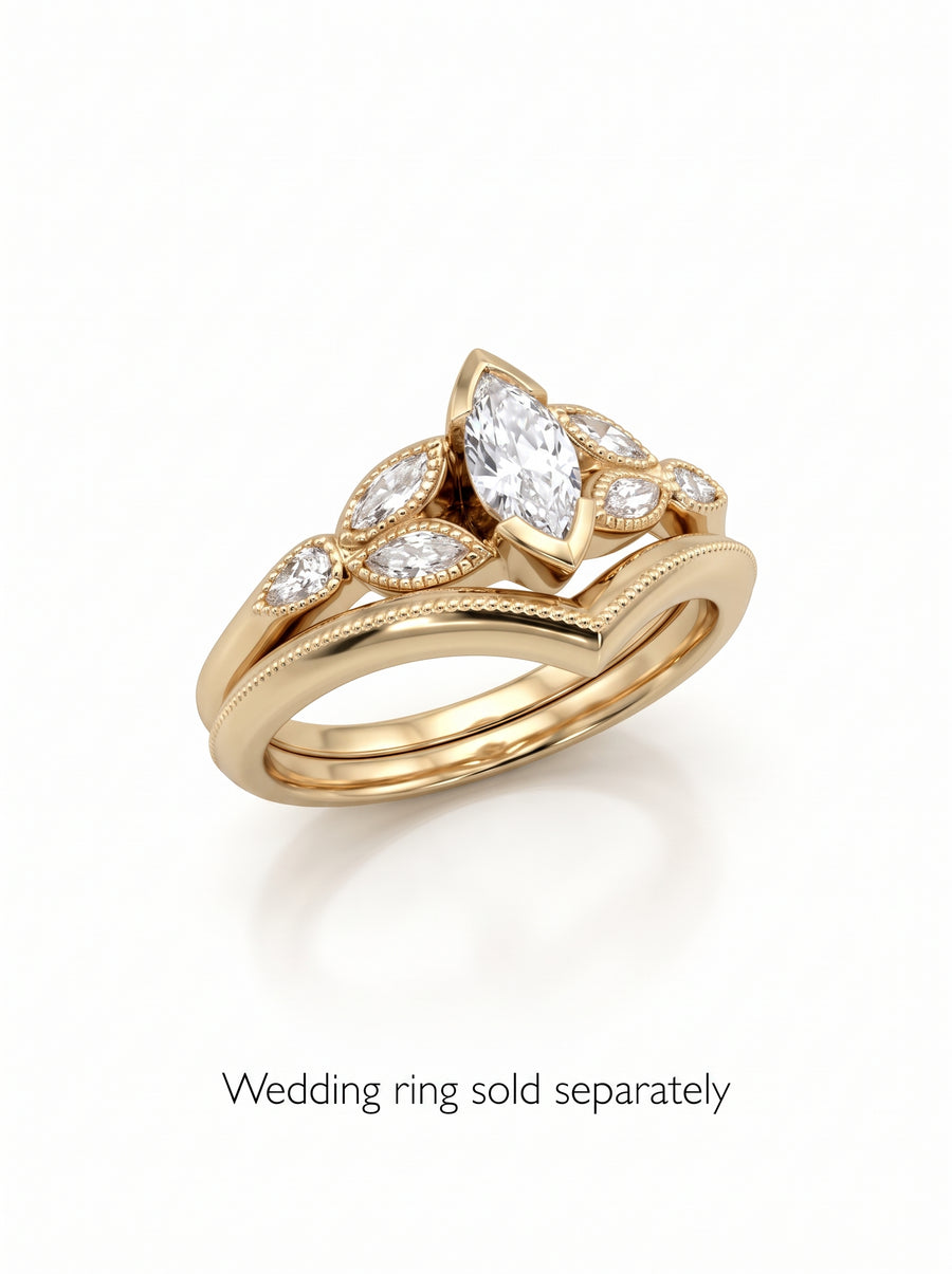 Gold engagement ring set with a marquise cut diamond and smaller side stones on a chevron band.