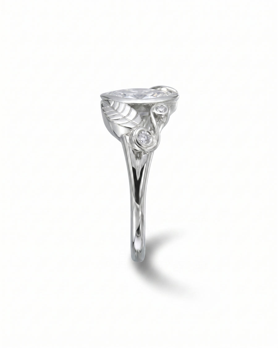 Silver ring with marquise diamond, two round diamonds, and a floral leaf design.