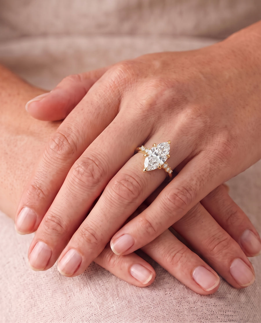 Marquise-cut lab-grown diamond engagement ring with a floral vine gold band on a woman's finger.
