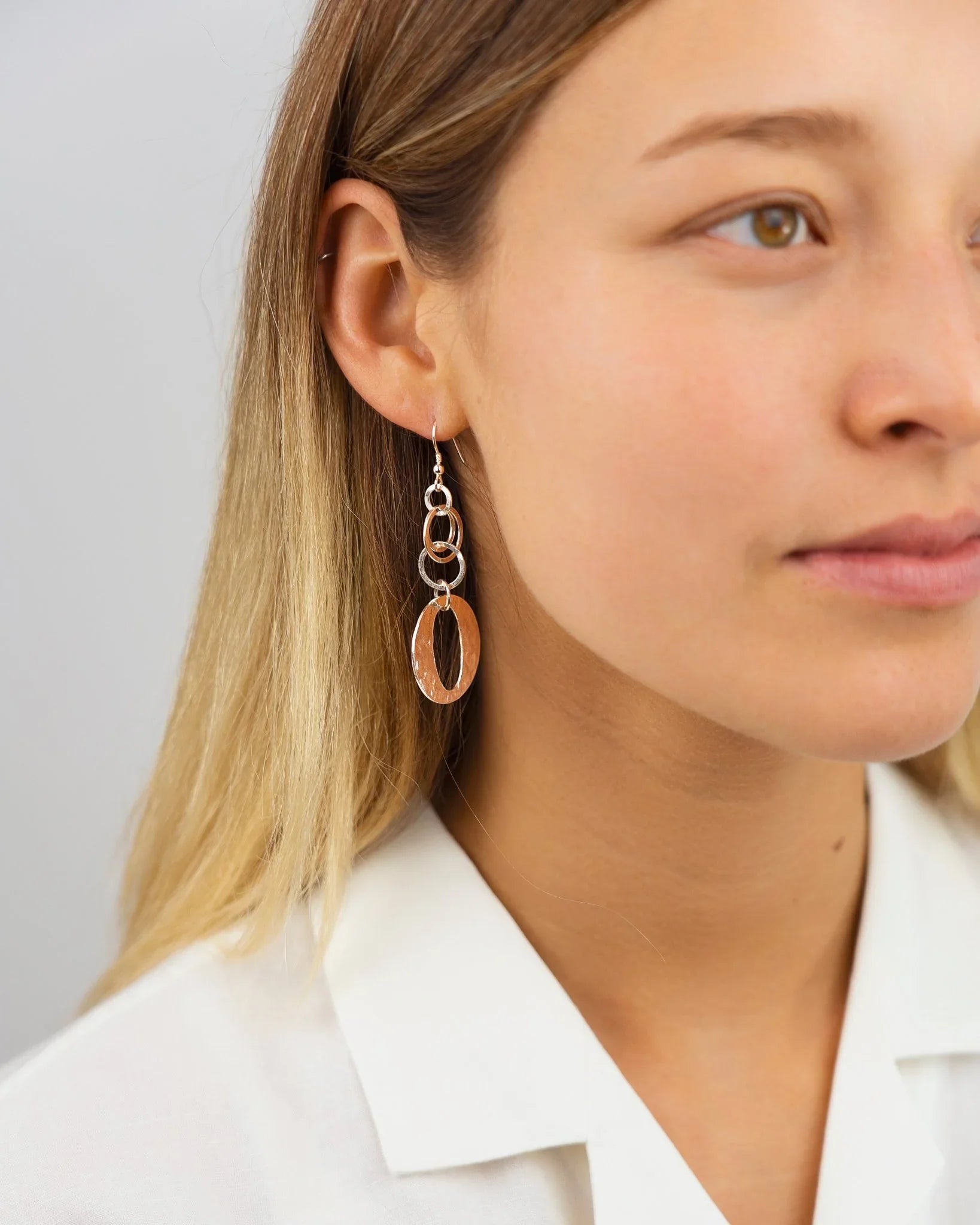 Woman wearing handcrafted hammered silver dangly earrings with oval and circle links