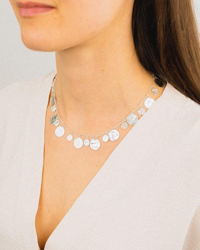 Woman wearing a hammered round silver necklace with organic textured discs