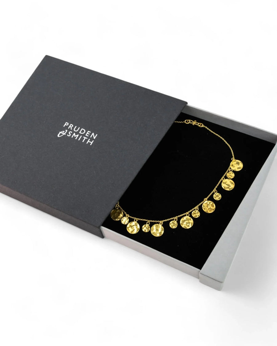 Hammered yellow gold round disc necklace with organic texture in a black gift box