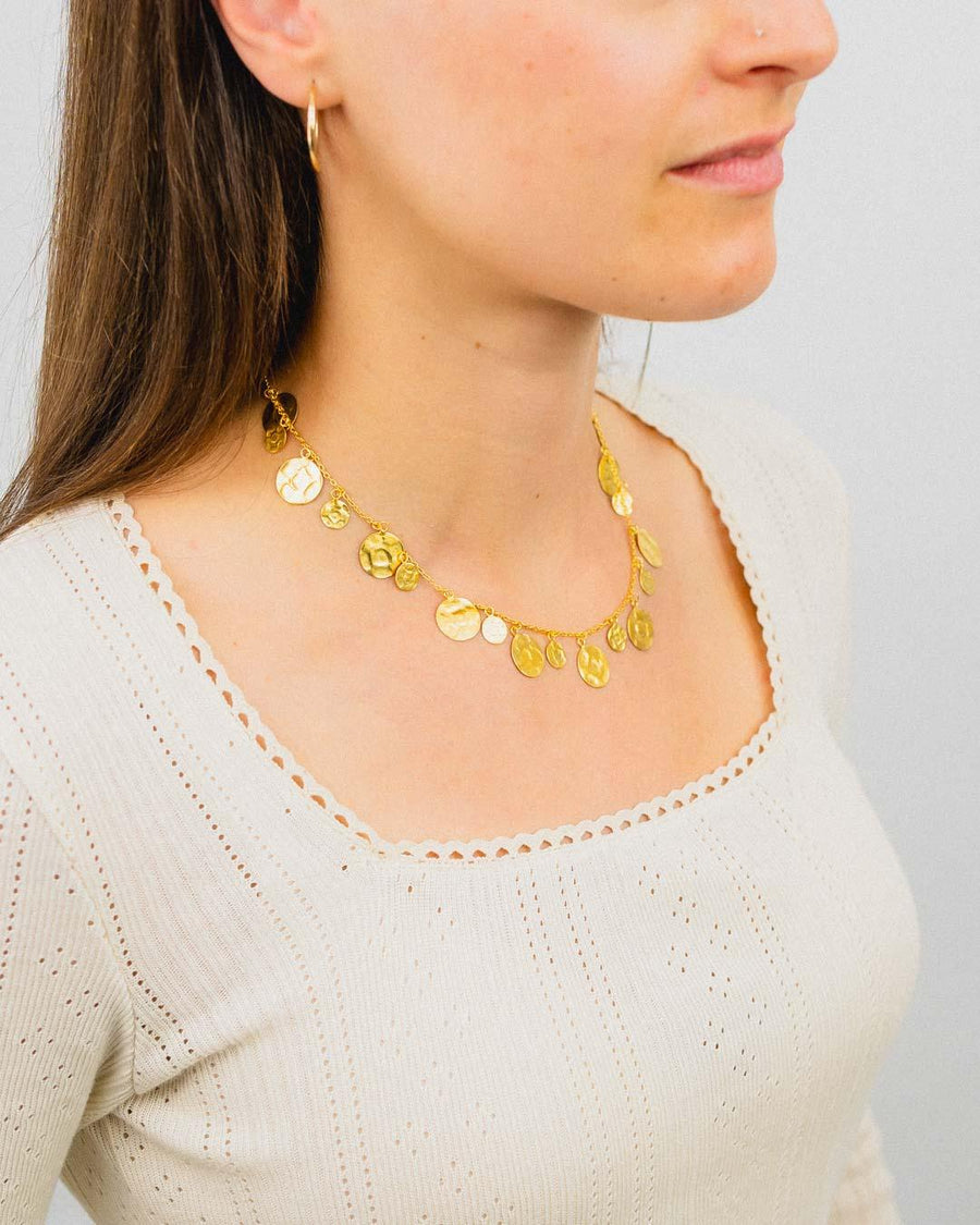 Woman wearing a hammered round yellow gold necklace with organic disc charms