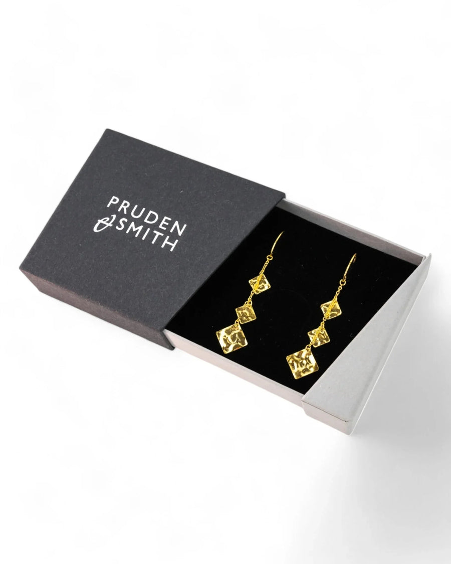 Gold hammered square dangly earrings in a black gift box.
