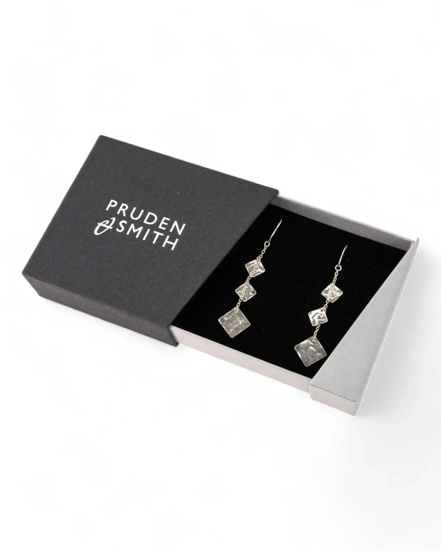 Silver hammered square dangly earrings in a black gift box.