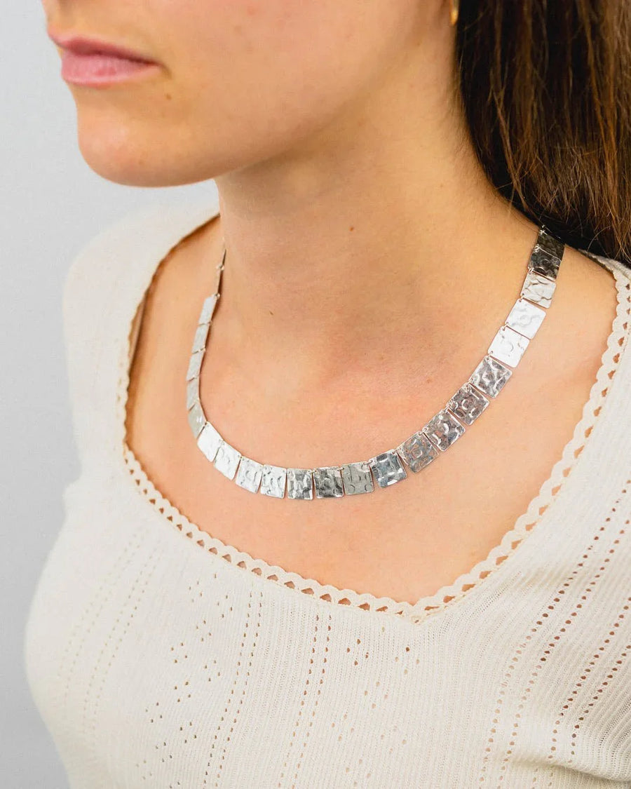 Handmade hammered silver square necklace on woman in cream knit top