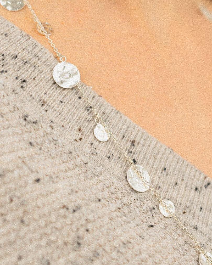 Handmade silver disc necklace with textured finish on a soft beige sweater