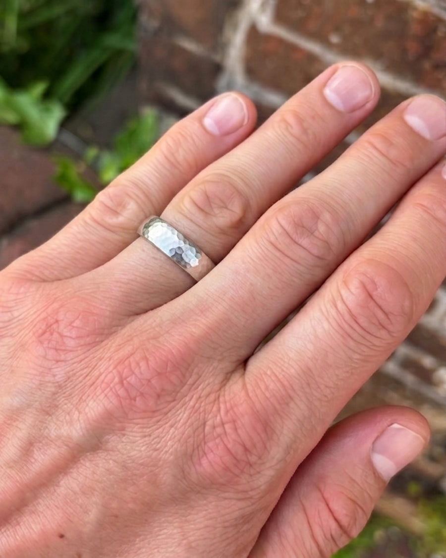 Silver matt hammered court wedding ring on a man's finger.