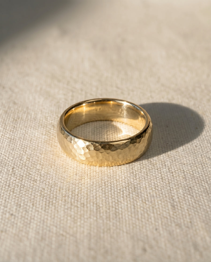 9ct yellow gold 4mm matt hammered court wedding ring on a light fabric.