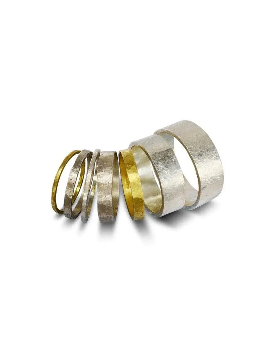 Seven rough hammered wedding rings in silver and gold.