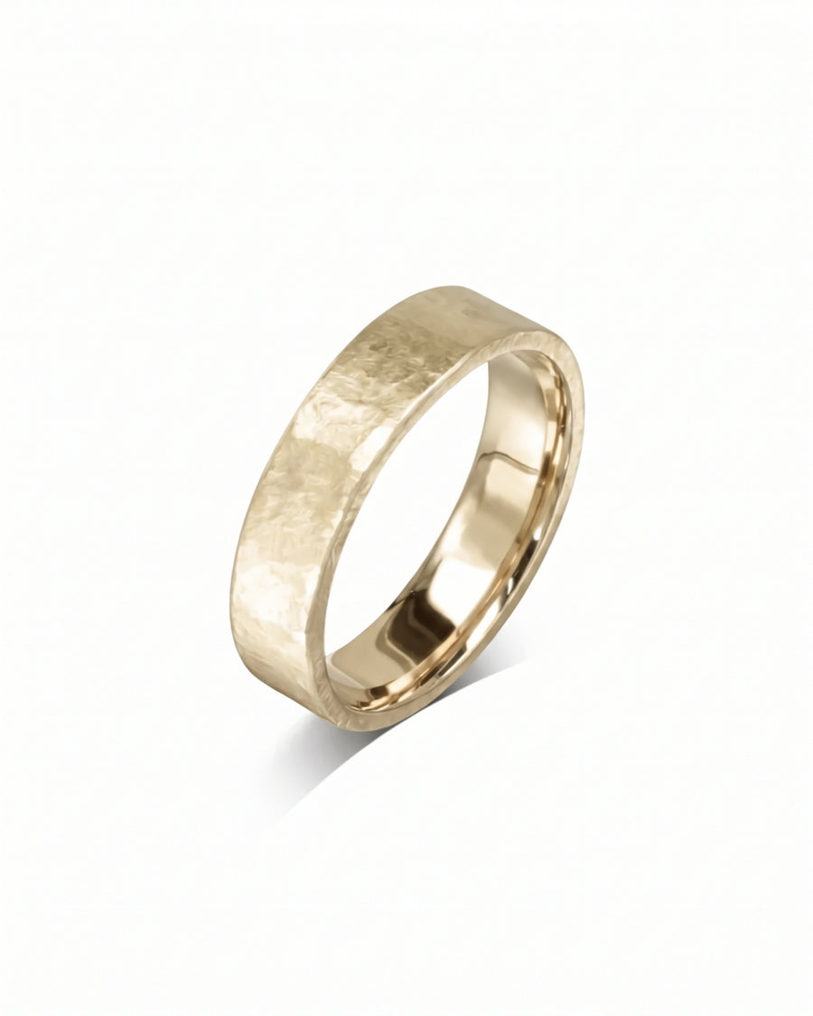 Gold wedding ring with a textured, rough hammered finish and a polished inner band.